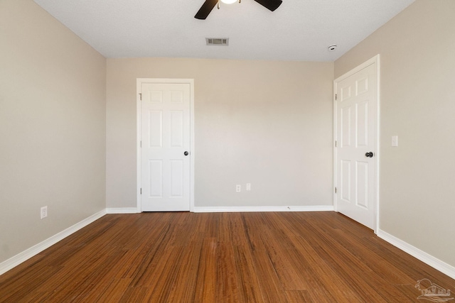 spare room featuring a ceiling fan, wood finished floors, visible vents, and baseboards