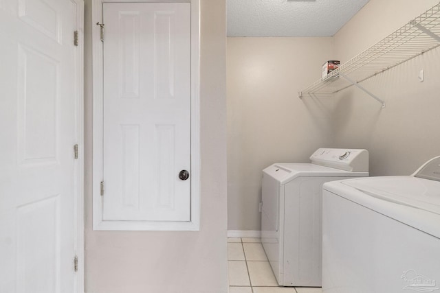 laundry area with laundry area, baseboards, a textured ceiling, separate washer and dryer, and light tile patterned flooring