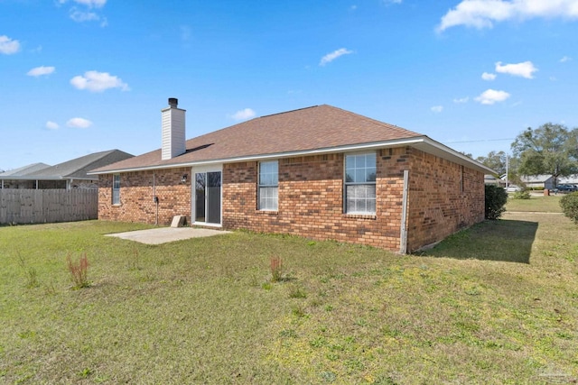 back of property with a lawn, a chimney, fence, a patio area, and brick siding