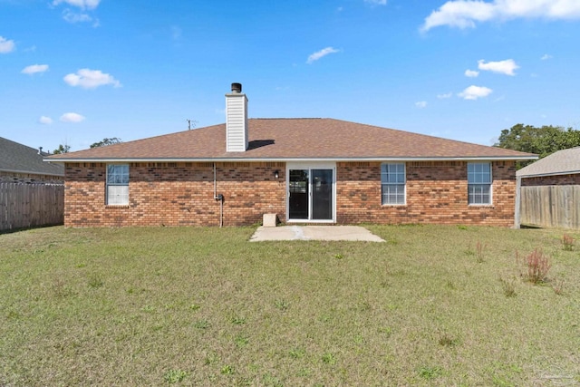 back of property with brick siding, a chimney, a fenced backyard, and a lawn