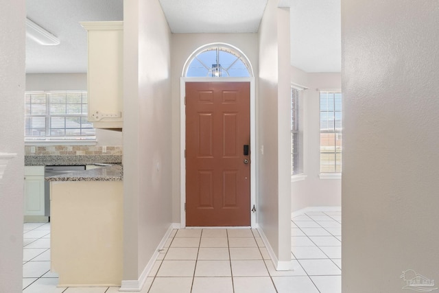 foyer entrance with light tile patterned floors, plenty of natural light, and baseboards