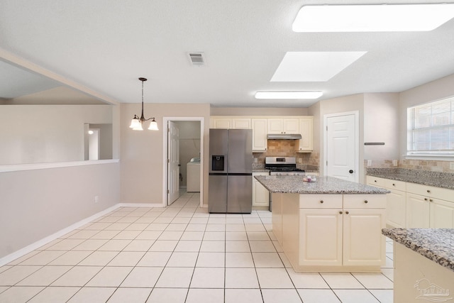 kitchen featuring tasteful backsplash, visible vents, appliances with stainless steel finishes, washer / dryer, and under cabinet range hood