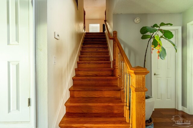 stairway featuring a textured ceiling and hardwood / wood-style flooring