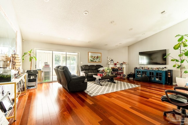 living room featuring a textured ceiling, vaulted ceiling, and hardwood / wood-style flooring