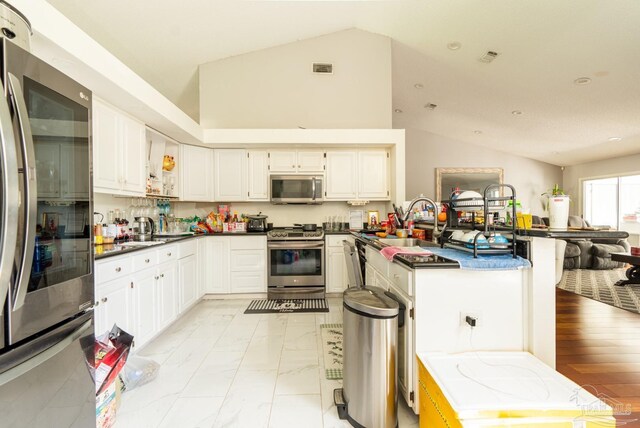 kitchen featuring high vaulted ceiling, stainless steel appliances, white cabinets, and light wood-type flooring