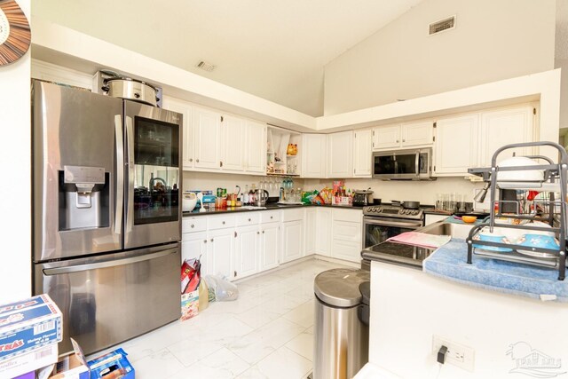 kitchen with high vaulted ceiling, stainless steel appliances, and white cabinetry