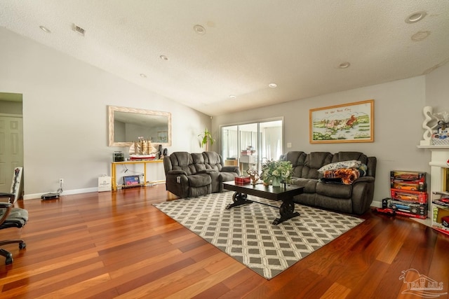 living room featuring wood-type flooring, vaulted ceiling, and a textured ceiling