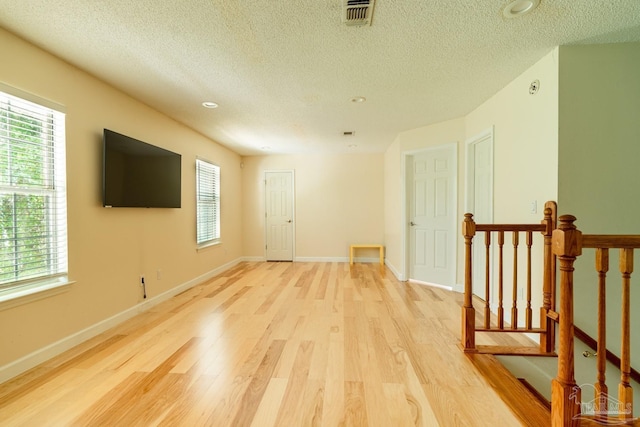 unfurnished room with a textured ceiling and light hardwood / wood-style flooring