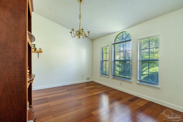 unfurnished room featuring an inviting chandelier, a textured ceiling, vaulted ceiling, and dark hardwood / wood-style flooring