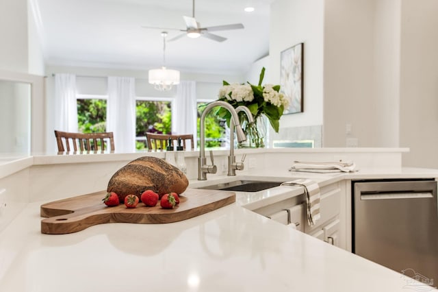 kitchen featuring a sink, dishwasher, white cabinetry, light countertops, and hanging light fixtures