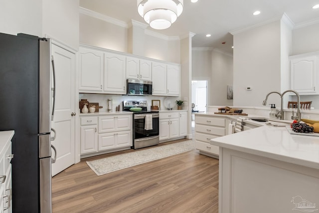 kitchen featuring crown molding, white cabinets, light wood finished floors, and appliances with stainless steel finishes