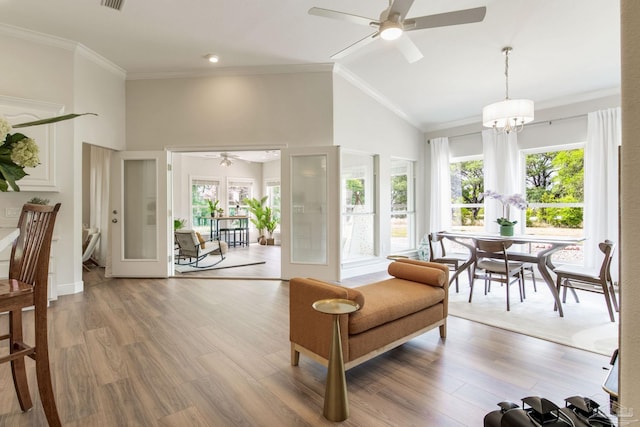 living area featuring wood finished floors, ceiling fan with notable chandelier, a healthy amount of sunlight, and high vaulted ceiling