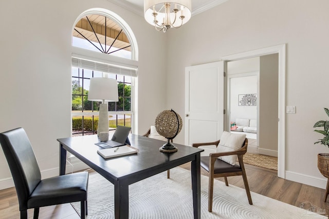 dining room featuring wood finished floors, baseboards, ornamental molding, and a notable chandelier