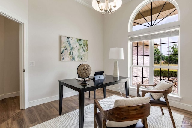 office space featuring wood finished floors, baseboards, ornamental molding, and a notable chandelier