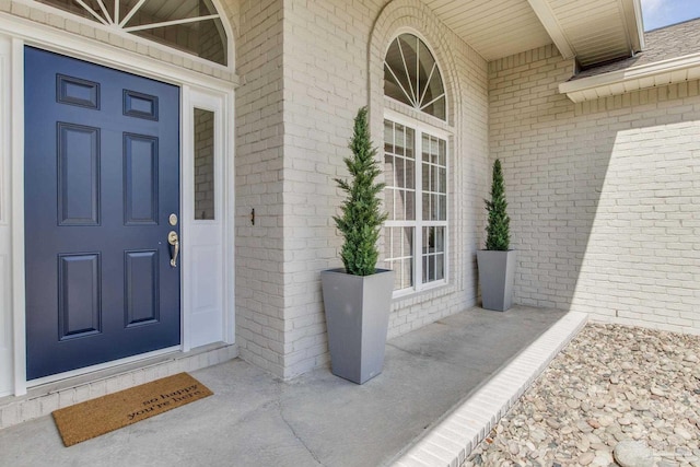 doorway to property with a porch and brick siding