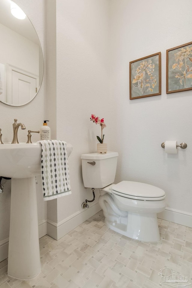 half bathroom with toilet and baseboards
