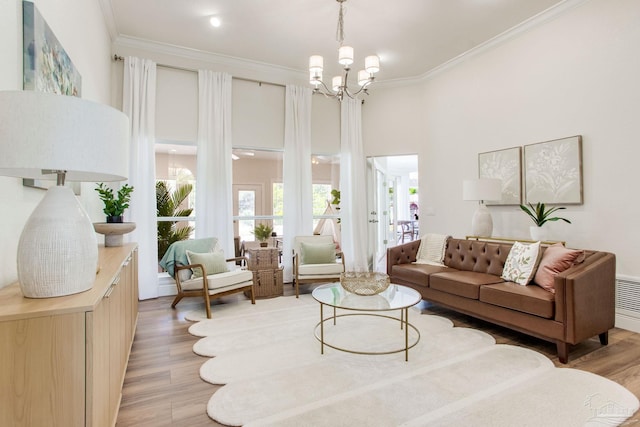 living area with light wood finished floors, crown molding, and an inviting chandelier