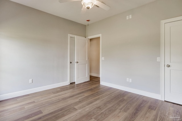 spare room with ceiling fan, light wood-style flooring, and baseboards