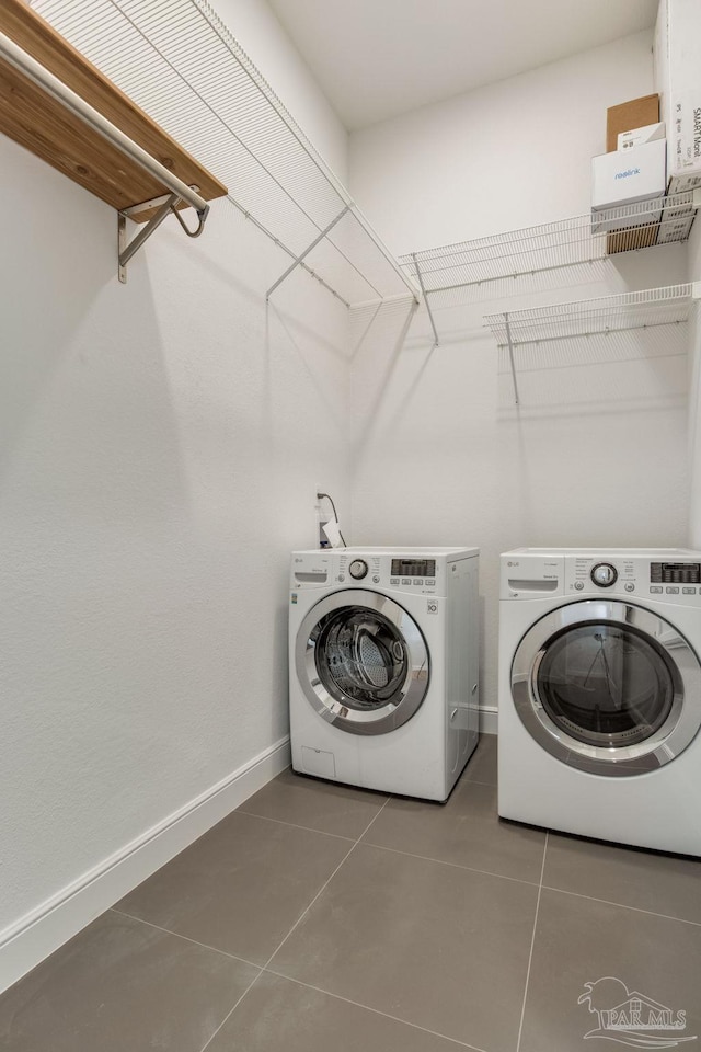 washroom with laundry area, independent washer and dryer, tile patterned flooring, and baseboards