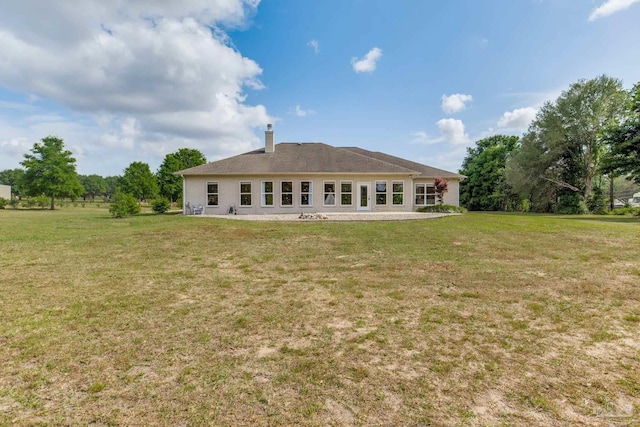back of property with a yard and a chimney