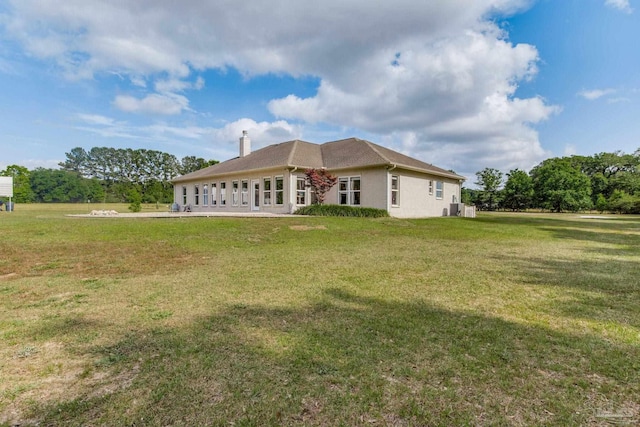 back of property featuring a chimney and a yard