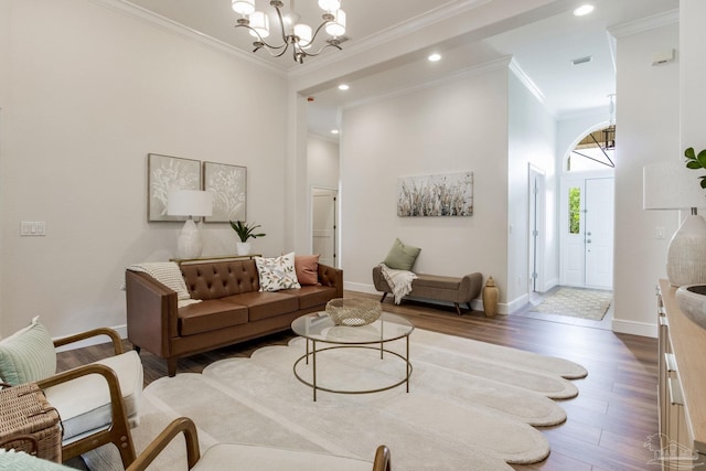 living area featuring a chandelier, crown molding, baseboards, and wood finished floors