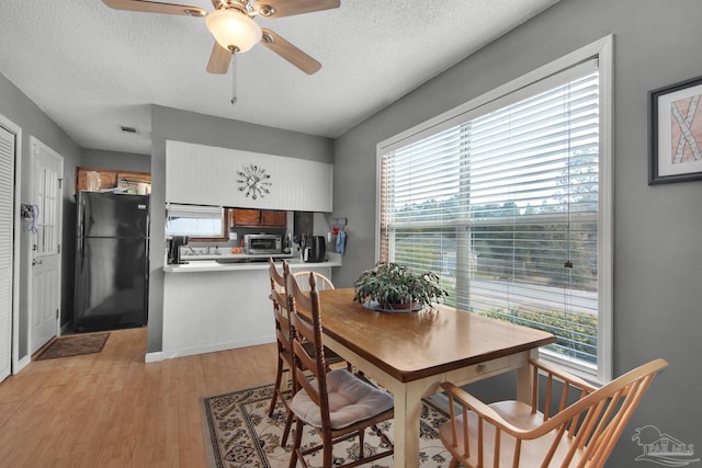 dining space featuring ceiling fan, light hardwood / wood-style flooring, and a textured ceiling