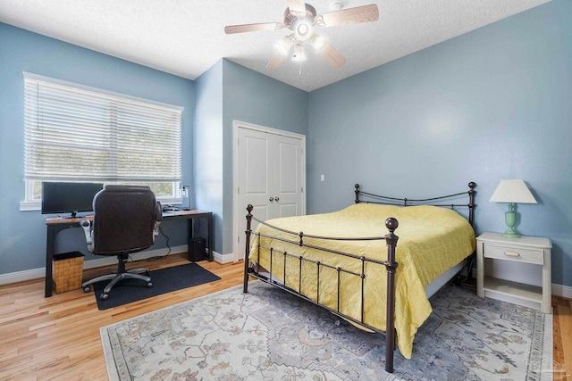 bedroom featuring light hardwood / wood-style flooring, a closet, a textured ceiling, and ceiling fan