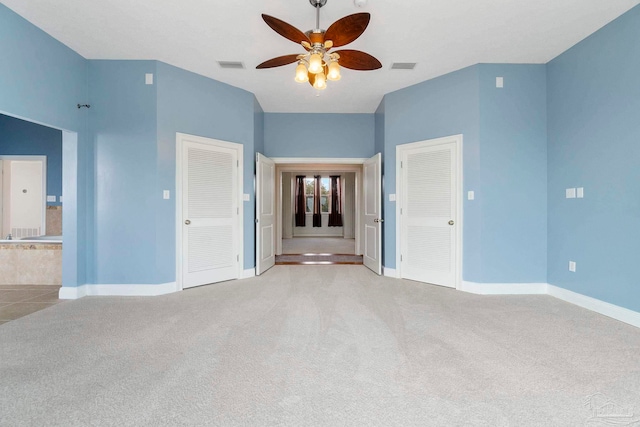 unfurnished bedroom featuring light carpet, ensuite bathroom, and ceiling fan