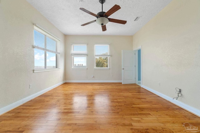 spare room featuring light wood-type flooring, ceiling fan, and a textured ceiling