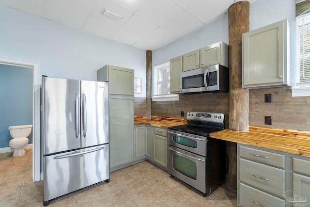 kitchen featuring butcher block countertops, a healthy amount of sunlight, and appliances with stainless steel finishes