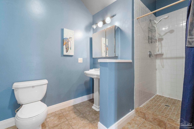 bathroom featuring tiled shower, tile patterned floors, and toilet