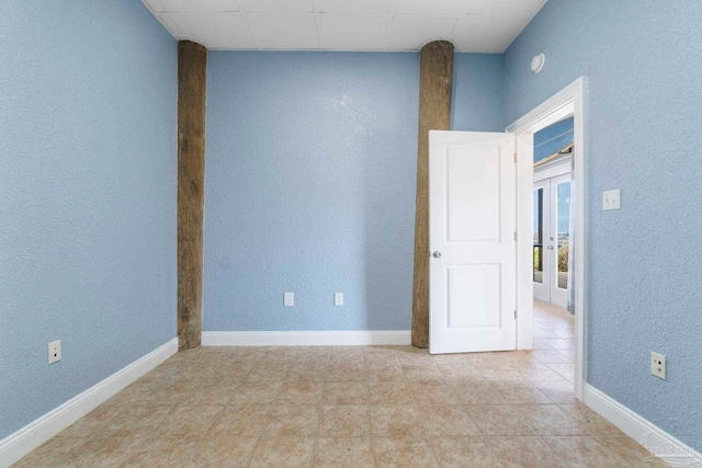 empty room featuring light tile patterned flooring and french doors