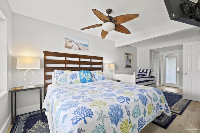 bedroom featuring ceiling fan, dark wood-type flooring, and beam ceiling