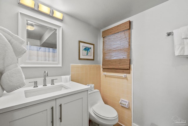 bathroom with toilet, vanity, and tile walls