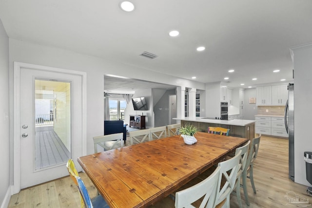 dining room with decorative columns and light hardwood / wood-style flooring