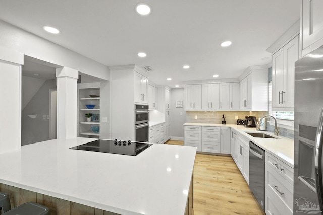 kitchen featuring a breakfast bar area, stainless steel appliances, white cabinets, and sink