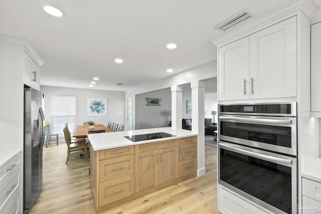 kitchen featuring light brown cabinetry, white cabinetry, appliances with stainless steel finishes, and light wood-type flooring