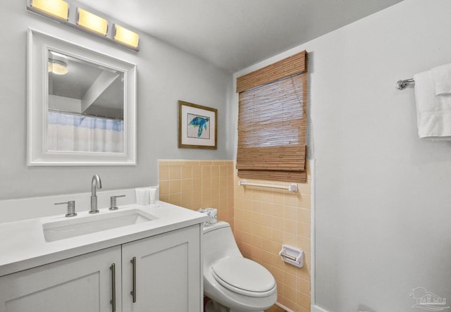 bathroom with toilet, vanity, and tile walls