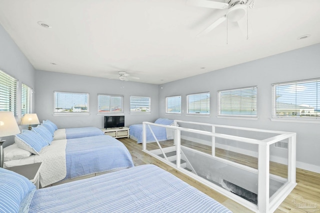 bedroom with light wood-type flooring, ceiling fan, and multiple windows