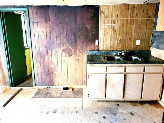 kitchen with a sink, dark countertops, and wooden walls