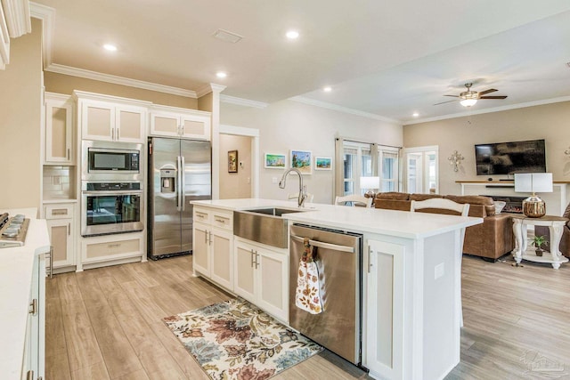 kitchen with light hardwood / wood-style flooring, white cabinets, a kitchen island with sink, and stainless steel appliances