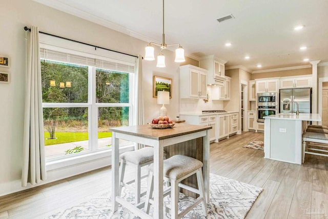 kitchen with stainless steel appliances, plenty of natural light, decorative light fixtures, and white cabinetry