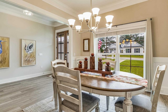 dining space with hardwood / wood-style floors, a notable chandelier, and crown molding