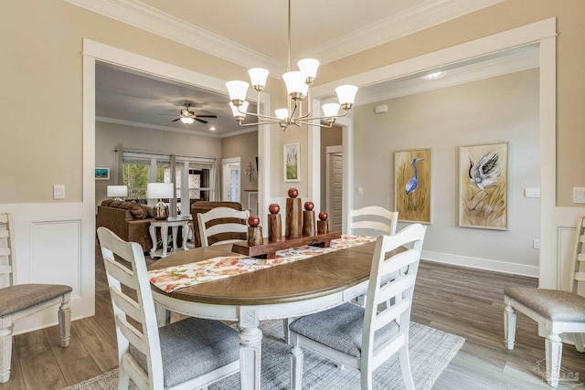 dining space featuring ornamental molding, ceiling fan with notable chandelier, and wood-type flooring