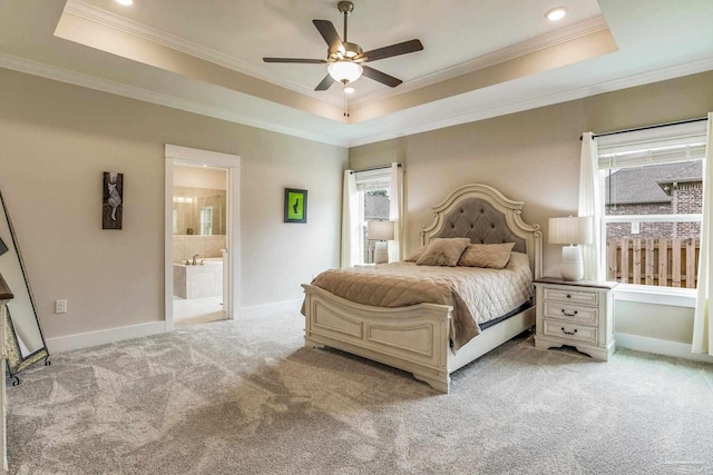 bedroom featuring ensuite bathroom, ceiling fan, light carpet, and a raised ceiling