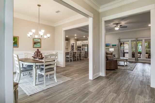 dining area featuring ornamental molding, hardwood / wood-style floors, and ceiling fan with notable chandelier