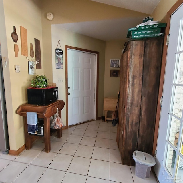 foyer featuring light tile patterned flooring and baseboards