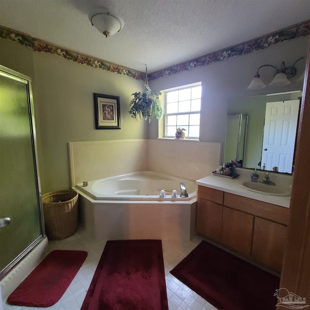 bathroom with a bath, a stall shower, a textured ceiling, and vanity