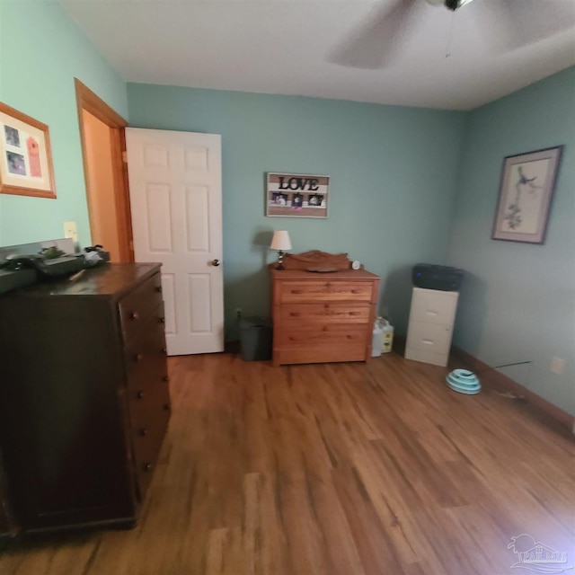 bedroom featuring baseboards, wood finished floors, and a ceiling fan